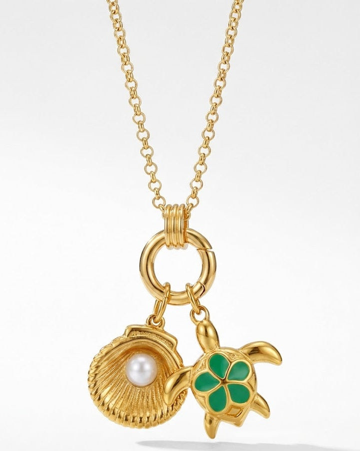 Gold necklace with shell, pearl, and turtle charm on a white background