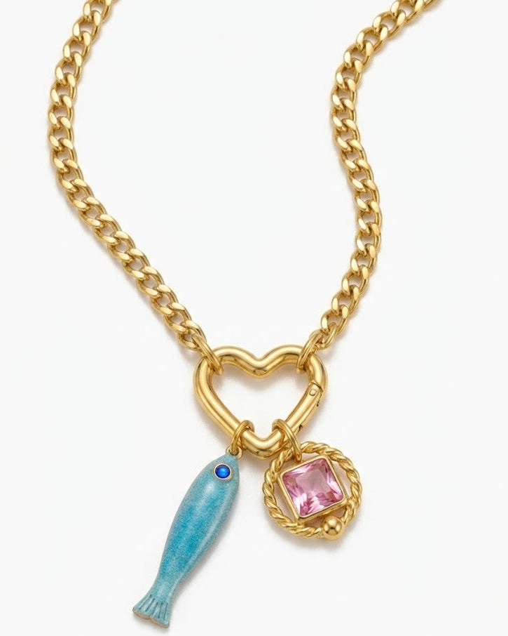 Gold chain necklace with heart-shaped clasp, blue fish charm, and pink gemstone on a white background