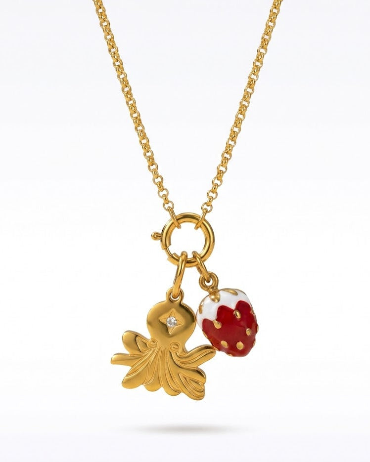 Gold necklace with a small gold  octopus and red strawberry on a white background