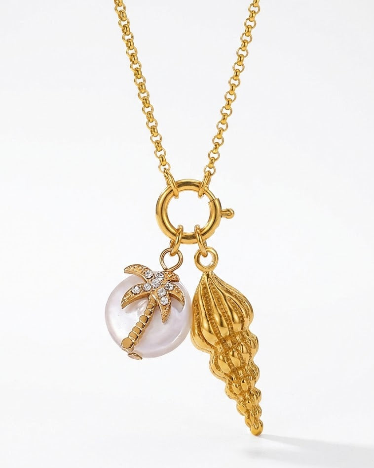 Gold necklace with a palm tree and shell charm on a white background